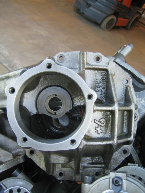 1990 Ford Bronco - Close-up of a disassembled differential center casting marked NODULAR IRON with a forklift in the background.