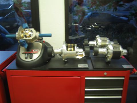 1990 Ford Bronco - Cutaway differential and locker display models sit atop a red rolling tool chest near a storefront window.