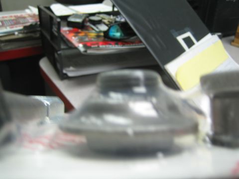 1990 Ford Bronco - out-of-focus close-up of a cone-shaped dark metal part in clamshell packaging on a desk.