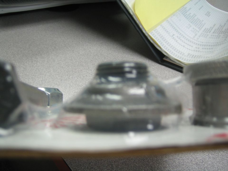 Blurry close-up of metal hardware parts in packaging on a desk
