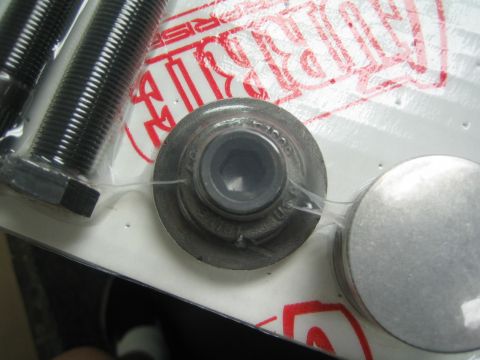 1990 Ford Bronco - Close-up of a splined metal hub end and two black bolts on plastic packaging with red printed text.