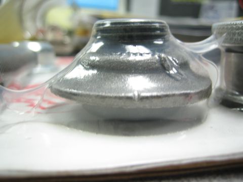 1990 Ford Bronco - Close-up of a polished cone-shaped metal part with a threaded top sealed in clamshell packaging on a desk.