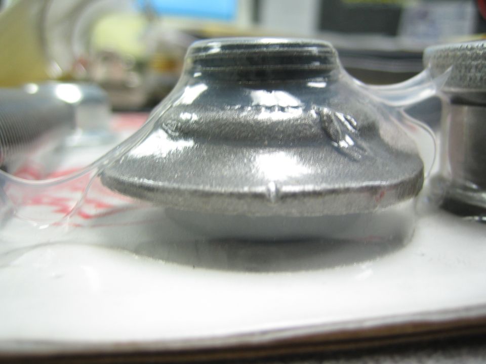 Close-up of a shiny cone-shaped metal part in packaging on a desk