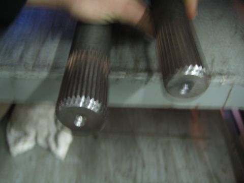 1990 Ford Bronco - blurry close-up of two splined steel axle shaft ends resting on a workbench.