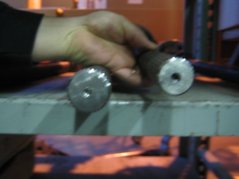 Hand holding two splined axle shafts upright on a green shop bench