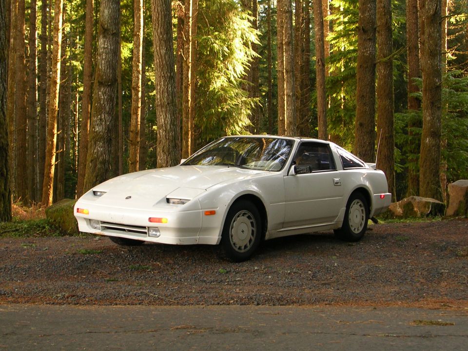 White Nissan 300ZX parked on gravel road in forest, 3/4 front view