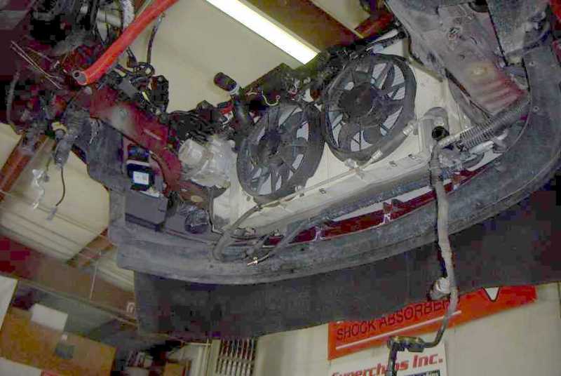 Underside view of car's engine bay, showing two large fans and various hoses and wiring