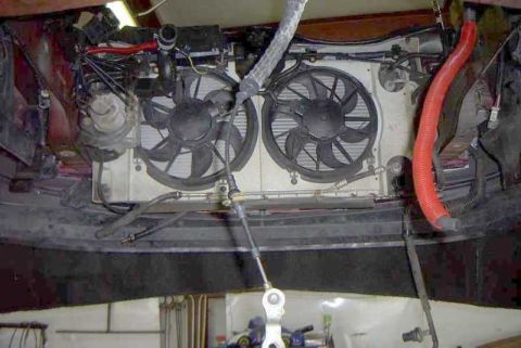 1997 Ford Taurus - Looking down into an engine bay stripped of its engine, showing the bare radiator support with dual electric cooling fans, the condenser an…