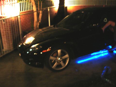 1993 Ford Taurus - A black car with blue underglow lighting is parked outdoors at night.
