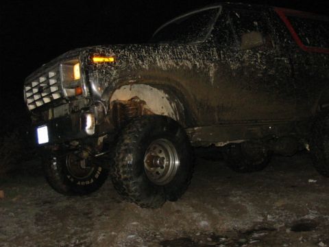 1982 Ford Bronco - This muddy SUV, likely from the 1980s, is seen off-road at night.