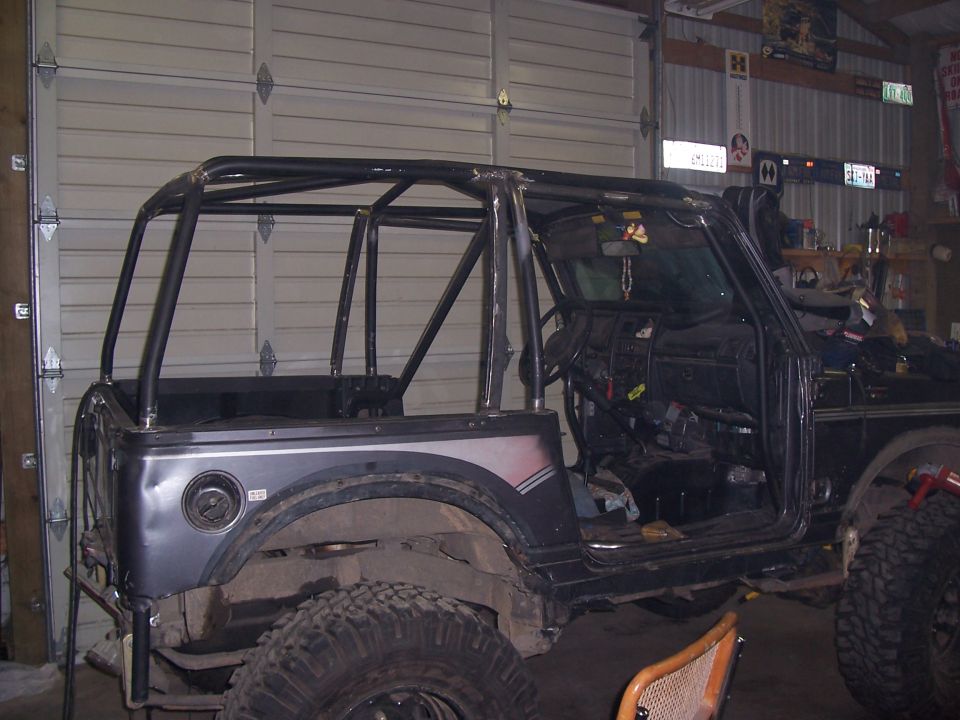 Gray Suzuki Samurai in garage, doors and top removed, custom roll cage and large mud tires