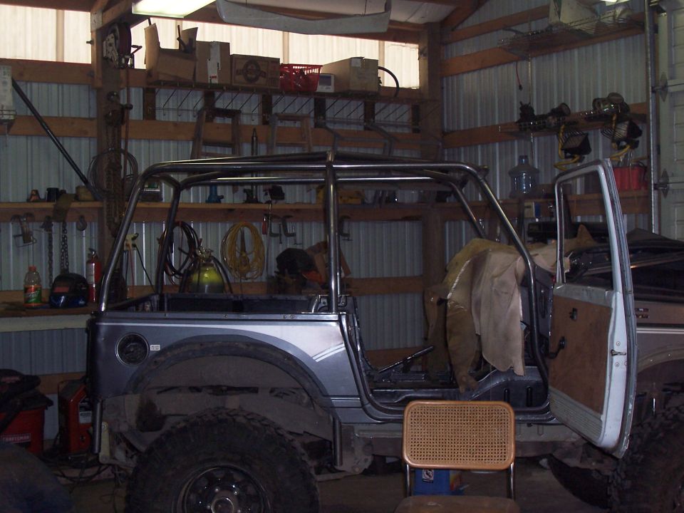 Side profile of a caged Suzuki project SUV with door open inside a workshop