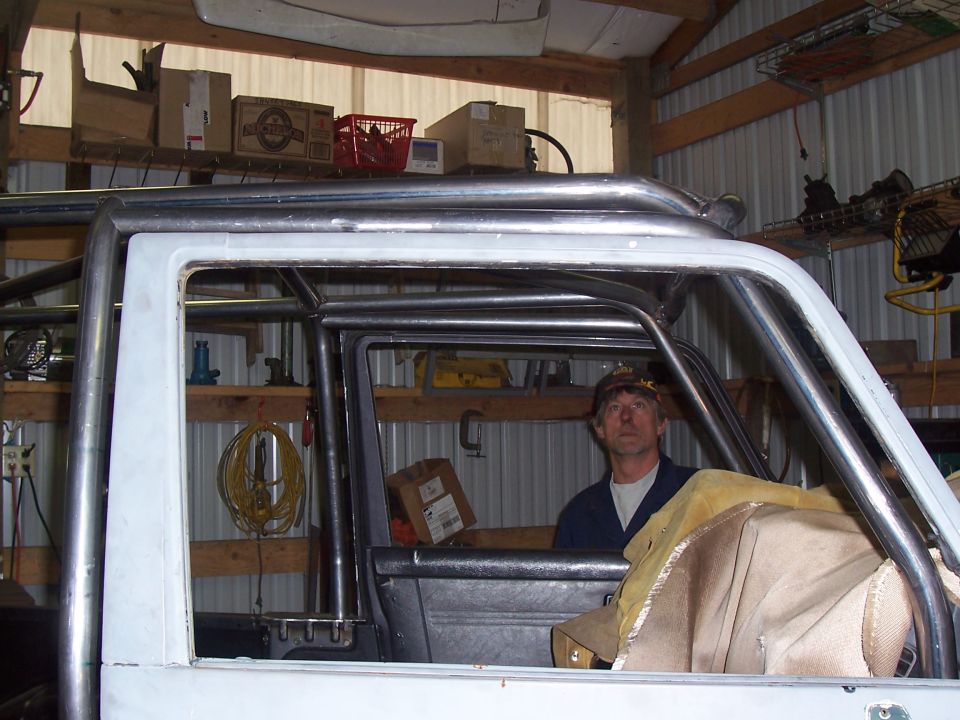 Man seated inside a caged project SUV looking out the door opening in a barn shop