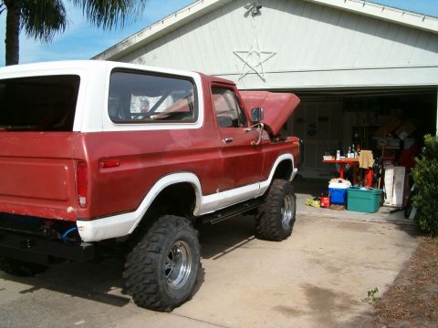 1979 Ford Bronco - This lifted Ford Bronco is parked in a driveway with its hood open, revealing the engine bay.