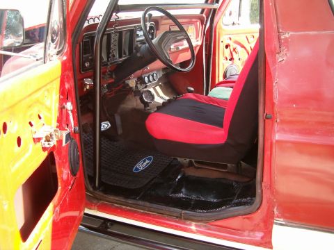 1979 Ford Bronco - Interior view of a red 1979 Ford Bronco, custom seat covers and a Ford-branded floor mat.