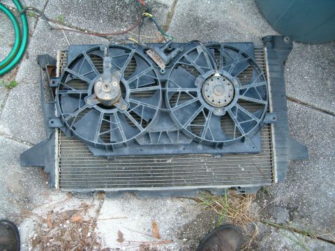 1979 Ford Bronco - Radiator and fan assembly removed from a vehicle, resting on a paved surface.