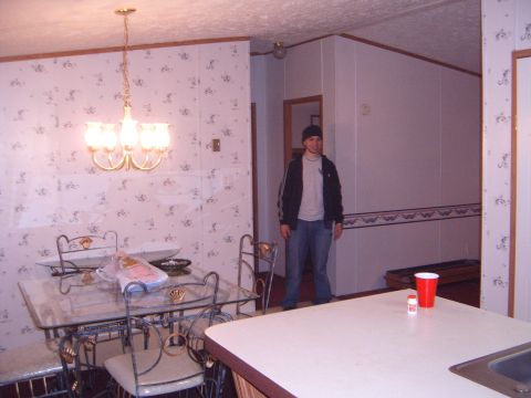 1988 Ford Bronco - A person stands in a room with a dining table and a counter, with wallpaper and wood paneling visible.