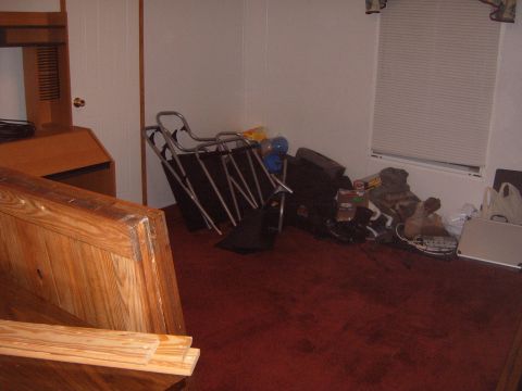 1988 Ford Bronco - The room appears to be used for storage, with various items cluttering the floor and a desk against the wall.