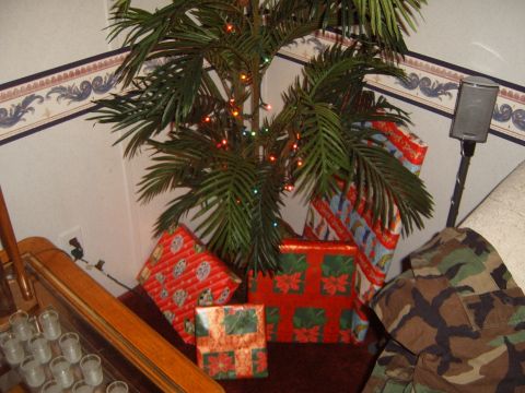 1988 Ford Bronco - A Christmas tree is decorated with lights and surrounded by wrapped gifts, with a camouflage jacket to the side.