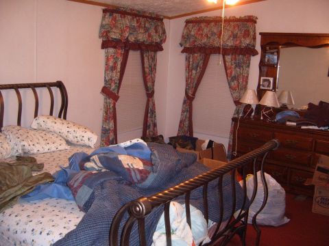 1988 Ford Bronco - Interior of a bedroom with a made bed, dresser, and windows covered by floral curtains.