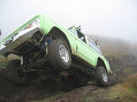 1999 Jeep Grand Cherokee - This lifted Ford Bronco is navigating a muddy off-road course.