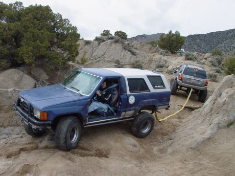 1999 Jeep Grand Cherokee - A Jeep Grand Cherokee tows a blue Toyota 4Runner through a challenging, rocky off-road course.