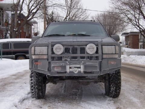 1996 Jeep Grand Cherokee - A 1996 Jeep Grand Cherokee is parked on a snowy street, equipped with a heavy-duty front bumper and winch.