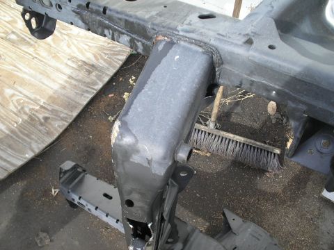 1991 Ford Taurus - A close-up view of a vehicle's frame, with a broom resting on the ground beneath it.