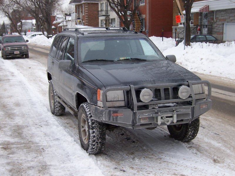 1996 Jeep Grand Cherokee with brush guard and winch parked on snowy street