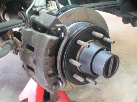 2000 Ford Excursion - Vehicle brake rotor and caliper assembly shown up close, supported by a red jack stand.