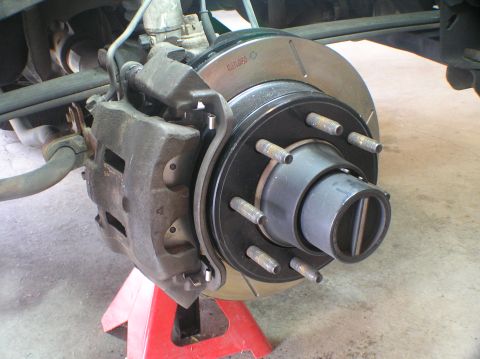 2000 Ford Excursion - Close-up view of a vehicle's brake rotor and caliper assembly, supported by a red jack.