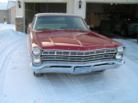 1967 Ford Galaxie - A red 1967 Ford Galaxie convertible sits in the snow outside a garage, with another vehicle visible inside.