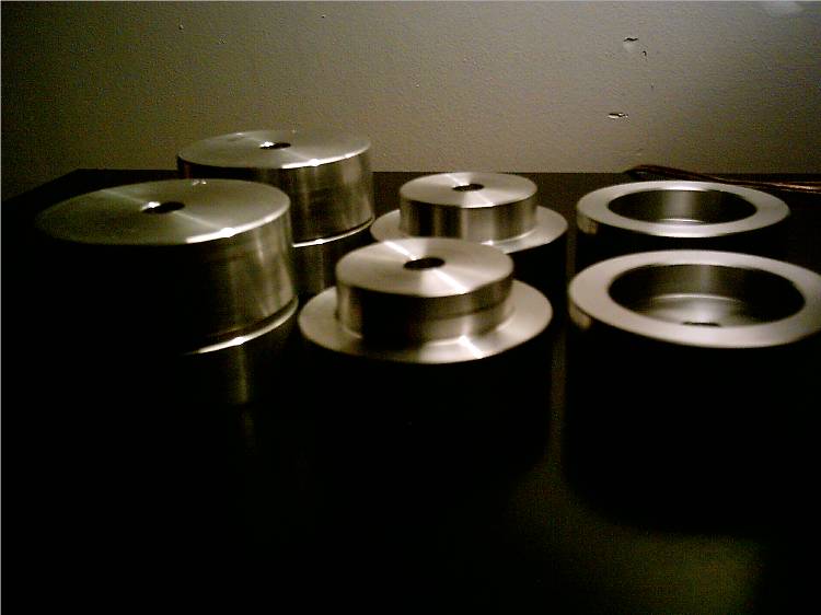 Six metal spacers with central holes, arranged on a dark surface