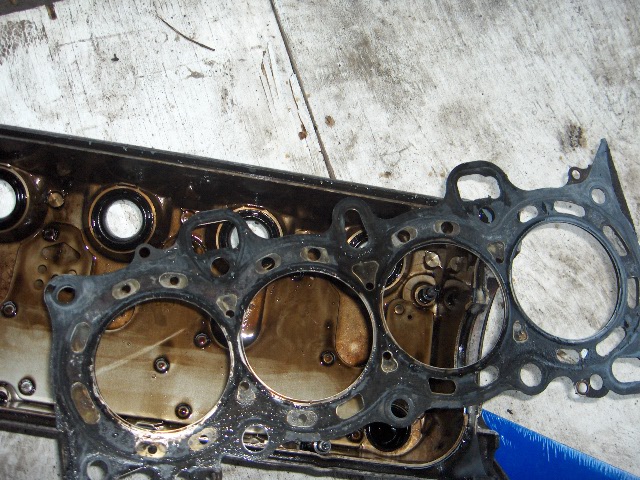 Used cylinder head gasket with four bores on oily engine surface