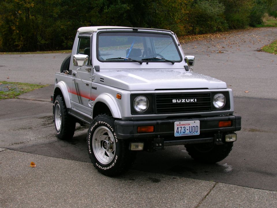 Silver Suzuki Samurai hardtop with red stripe and Washington plate parked on a paved road