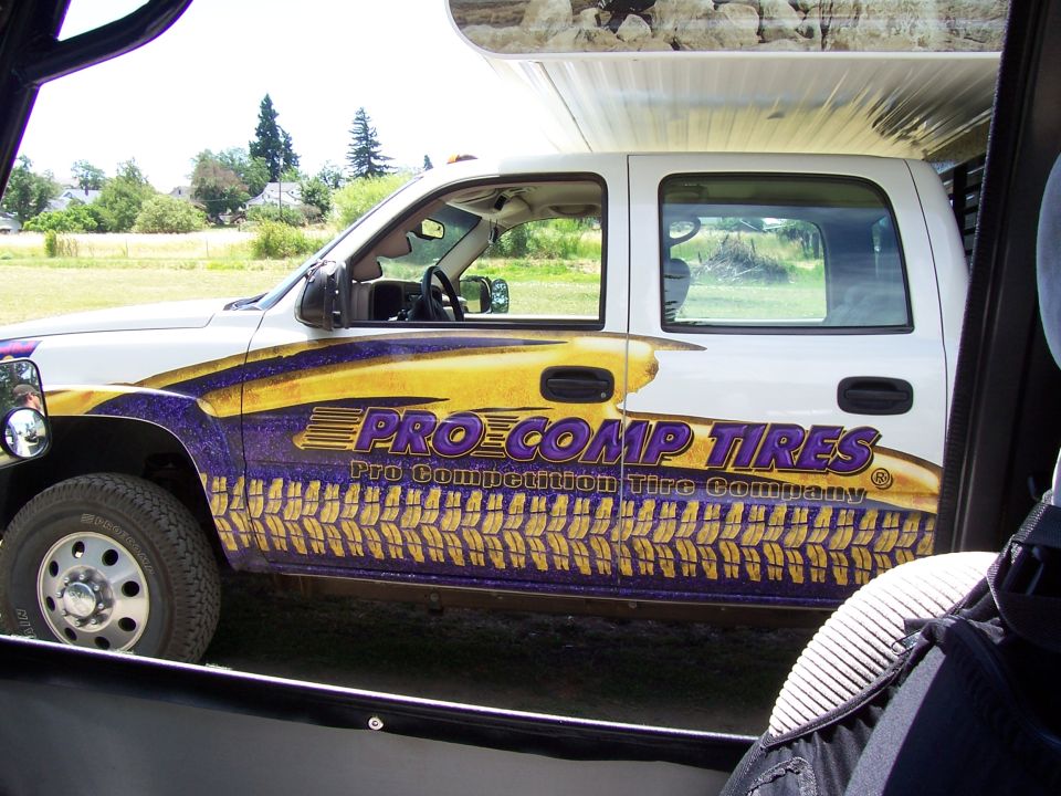 White and purple Pro Comp Tires pickup with body graphics seen through a vehicle doorway