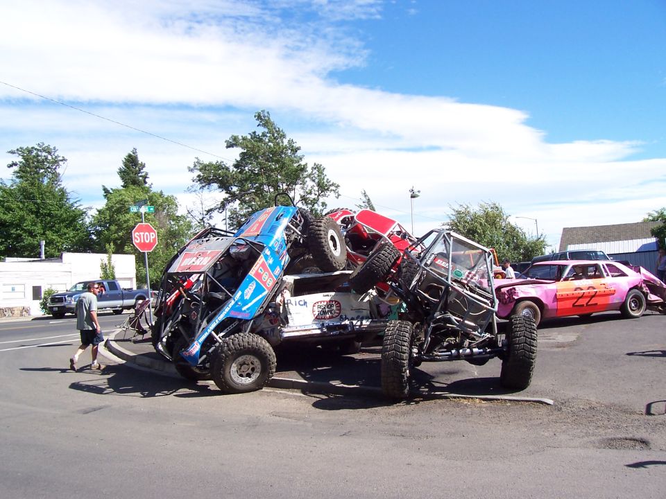 Blue, red and other rock buggies stacked over each other at a stop-sign intersection, pink stock car right