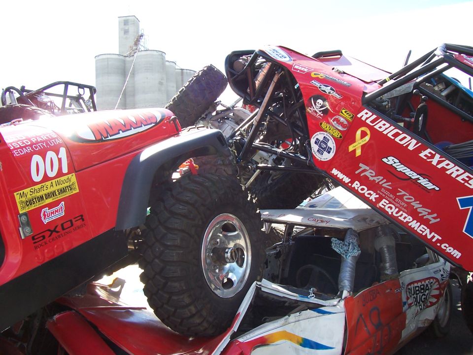 Red Rubicon Express buggy and red 001 Jeep wedged together amid bent metal