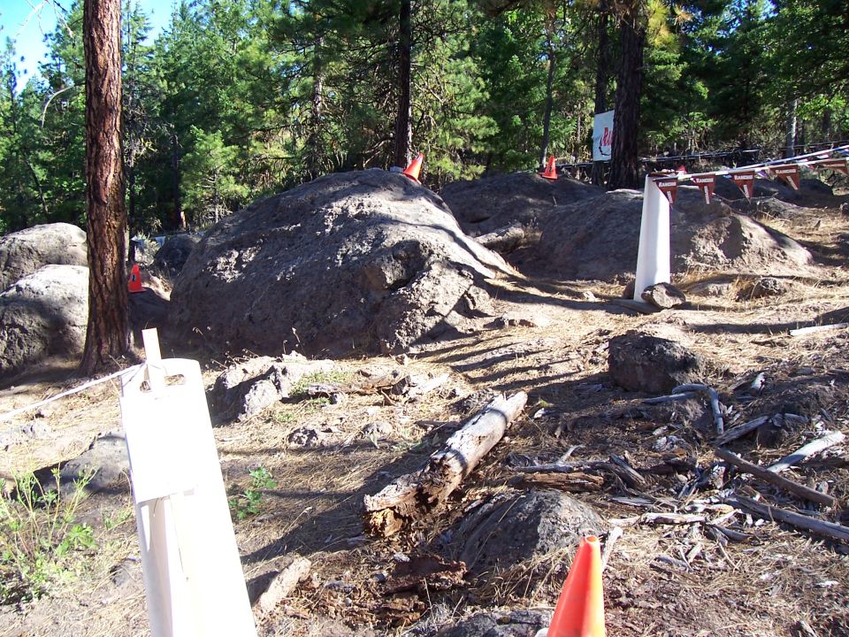 Forested rocky off-road course staked with cones and wooden markers