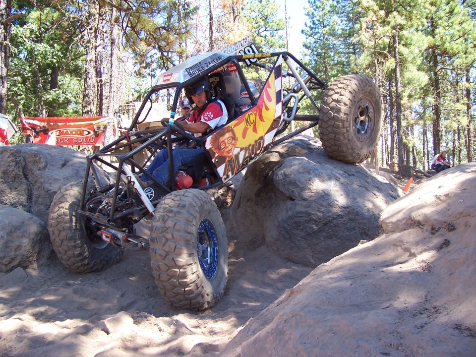 Driver in helmet pilots a tube buggy with cartoon decal through rock garden