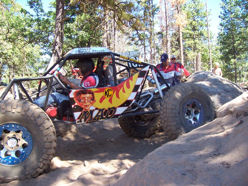 Tube buggy with flames and Mad cartoon panel climbing boulders, crew nearby