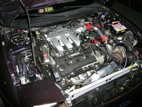1996 Ford Probe - Engine bay view of a Mazda V6 engine modified with a turbocharger and aftermarket intake system.