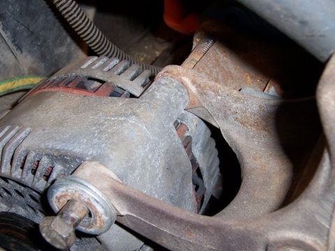 1983 Ford Bronco - Close-up view of an alternator and a rusty exhaust manifold, likely within an engine compartment.