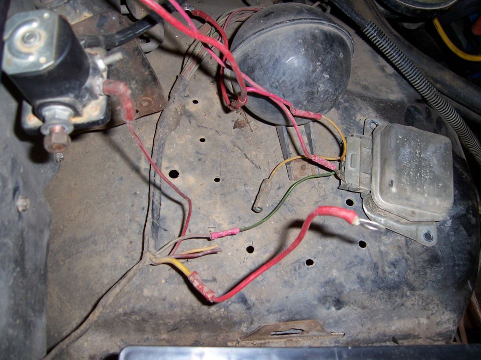 Close-up of engine bay wiring, including a solenoid, horn, and voltage regulator
