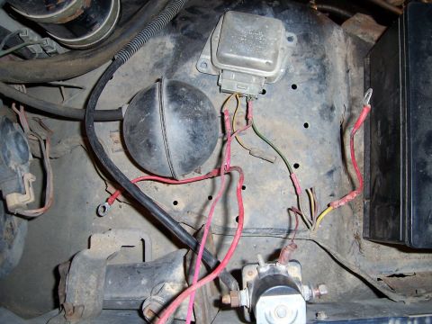 1983 Ford Bronco - This image shows various electrical parts within a vehicle's engine compartment, including wiring and a voltage regulator.