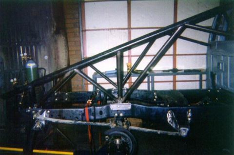 1977 Ford F-150 - Custom roll cage fabrication in progress on a truck chassis, with suspension and frame visible.