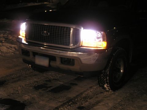 2000 Ford Excursion - The front grille and headlights of a Ford Excursion are visible at night, with snow on the ground.