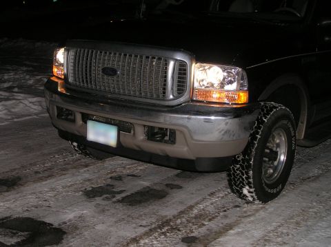 2000 Ford Excursion - Front view of a black Ford Excursion with headlights on, parked on a snowy road at night.