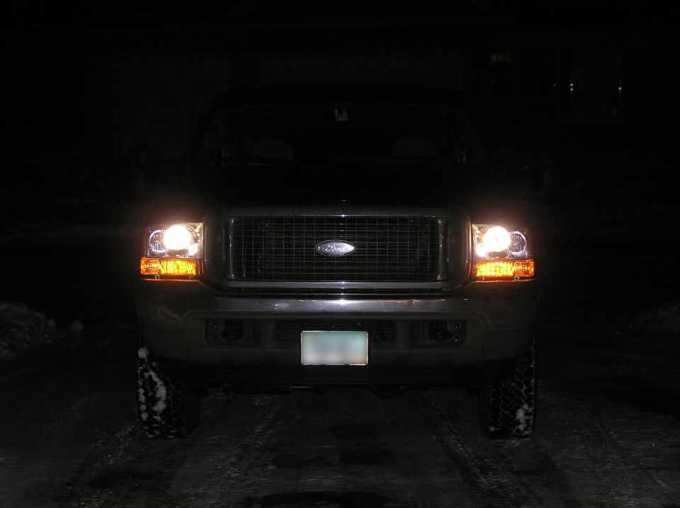 Front of dark Ford SUV at night with headlights on and chrome grille