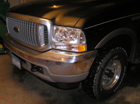 2000 Ford Excursion - The front passenger side of a black Ford Excursion is shown, with a focus on the headlight and grille.